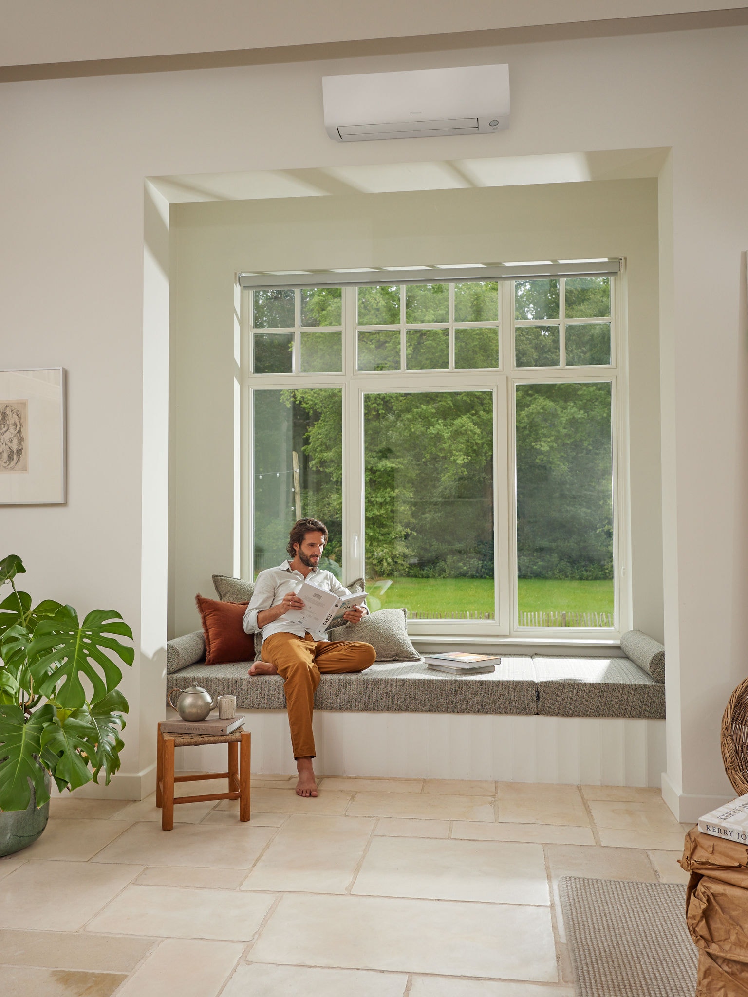 Uomo che legge una rivista in salotto, godendo di un'aria sana grazie alla pompa di calore aria-aria Daikin che fornisce aria pulita