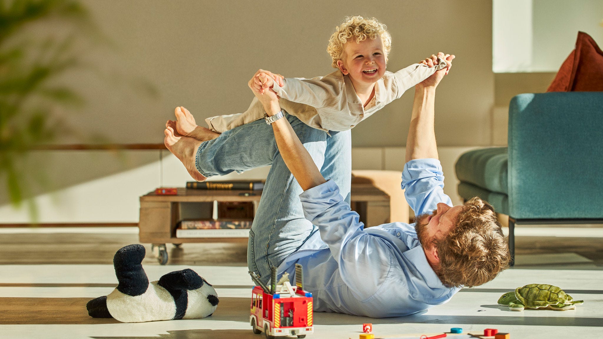 En far leger med sin søn på gulvet.