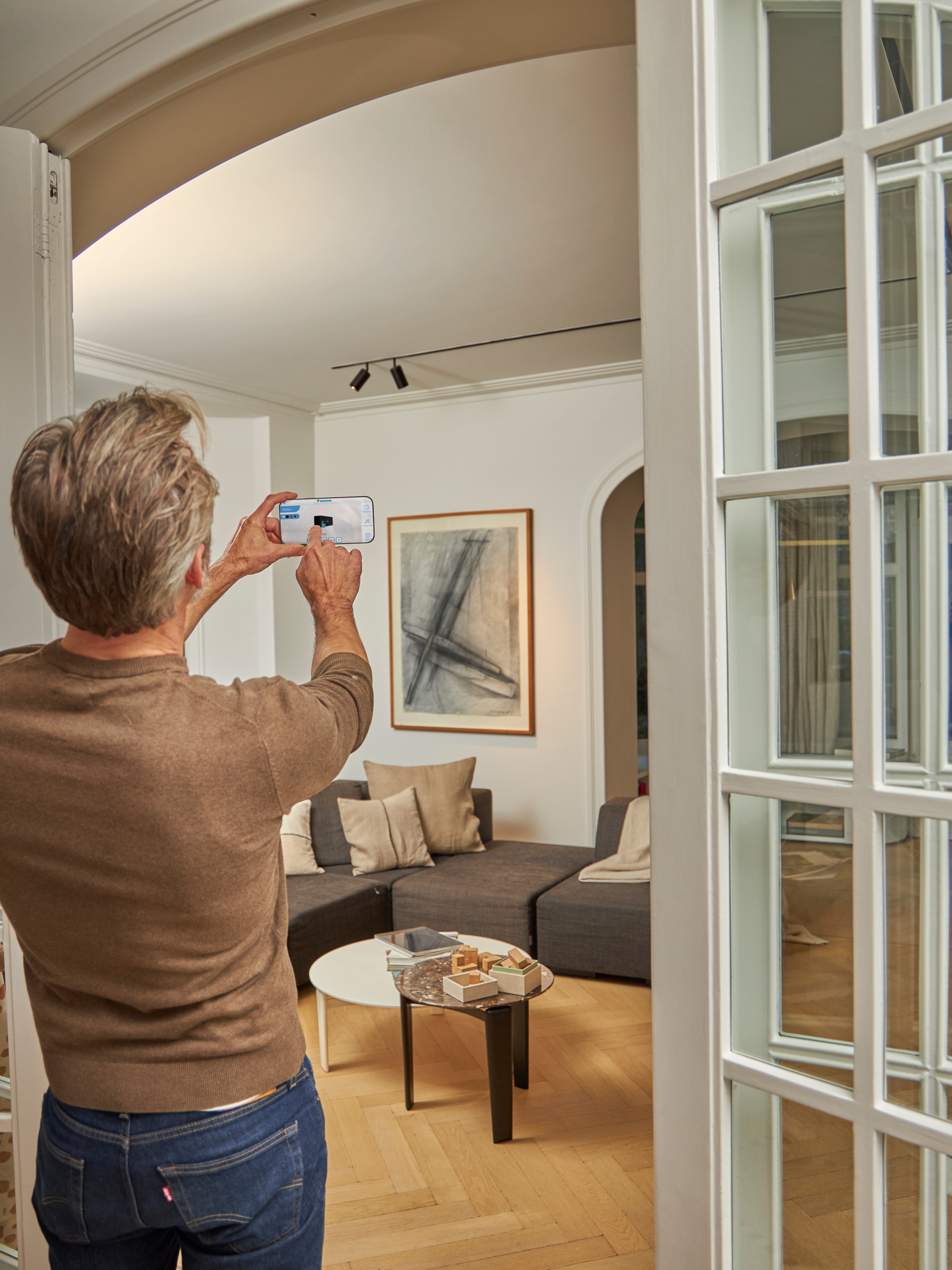 Un uomo mentre sta usando l'app 3D con realtà aumentata per visualizzare la pompa di calore aria-aria sia all'esterno che all'interno della sua casa