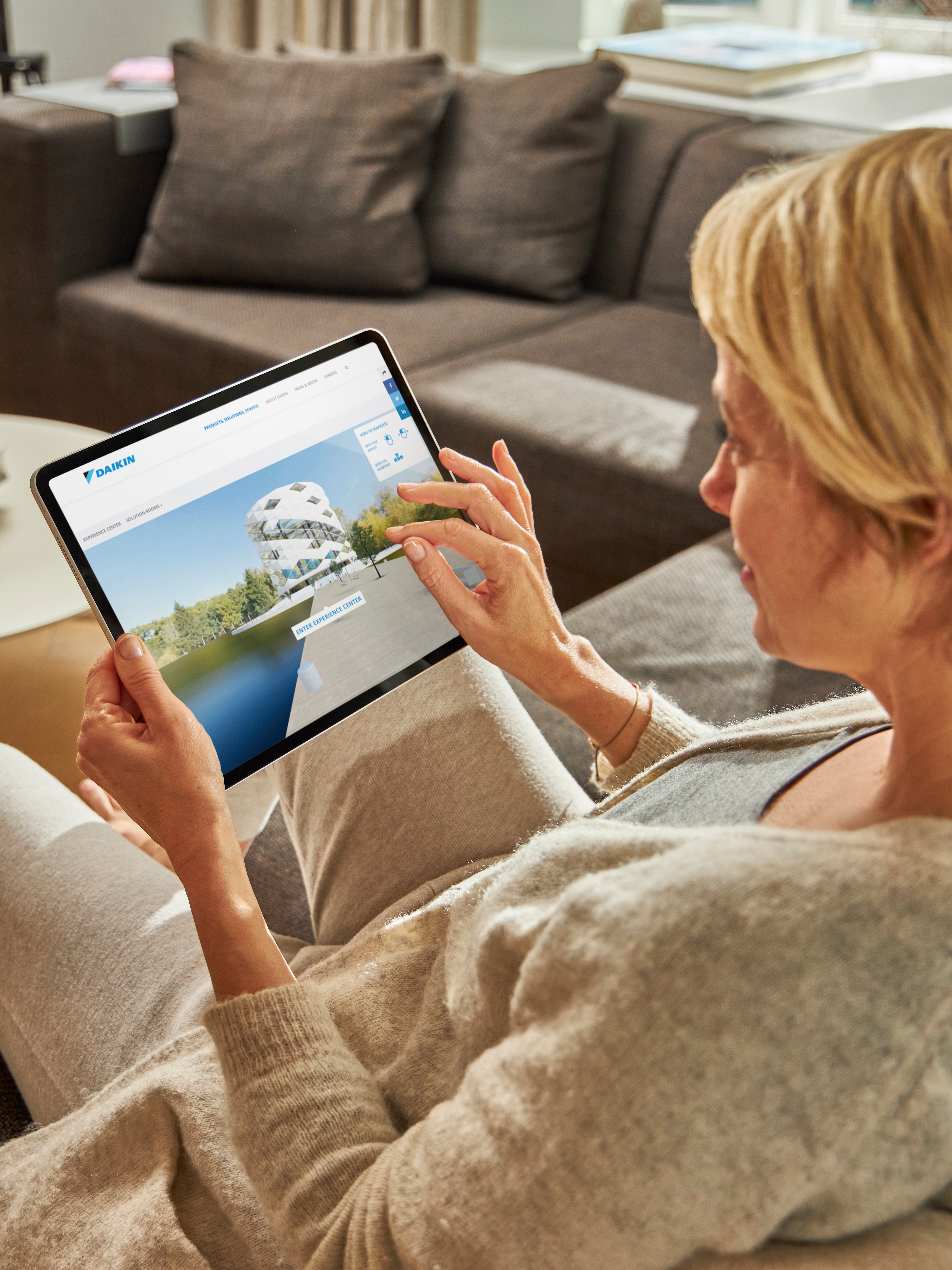 Una donna seduta su un divano intenta a guardare i climatizzatori nel centro di esperienza virtuale con il suo tablet