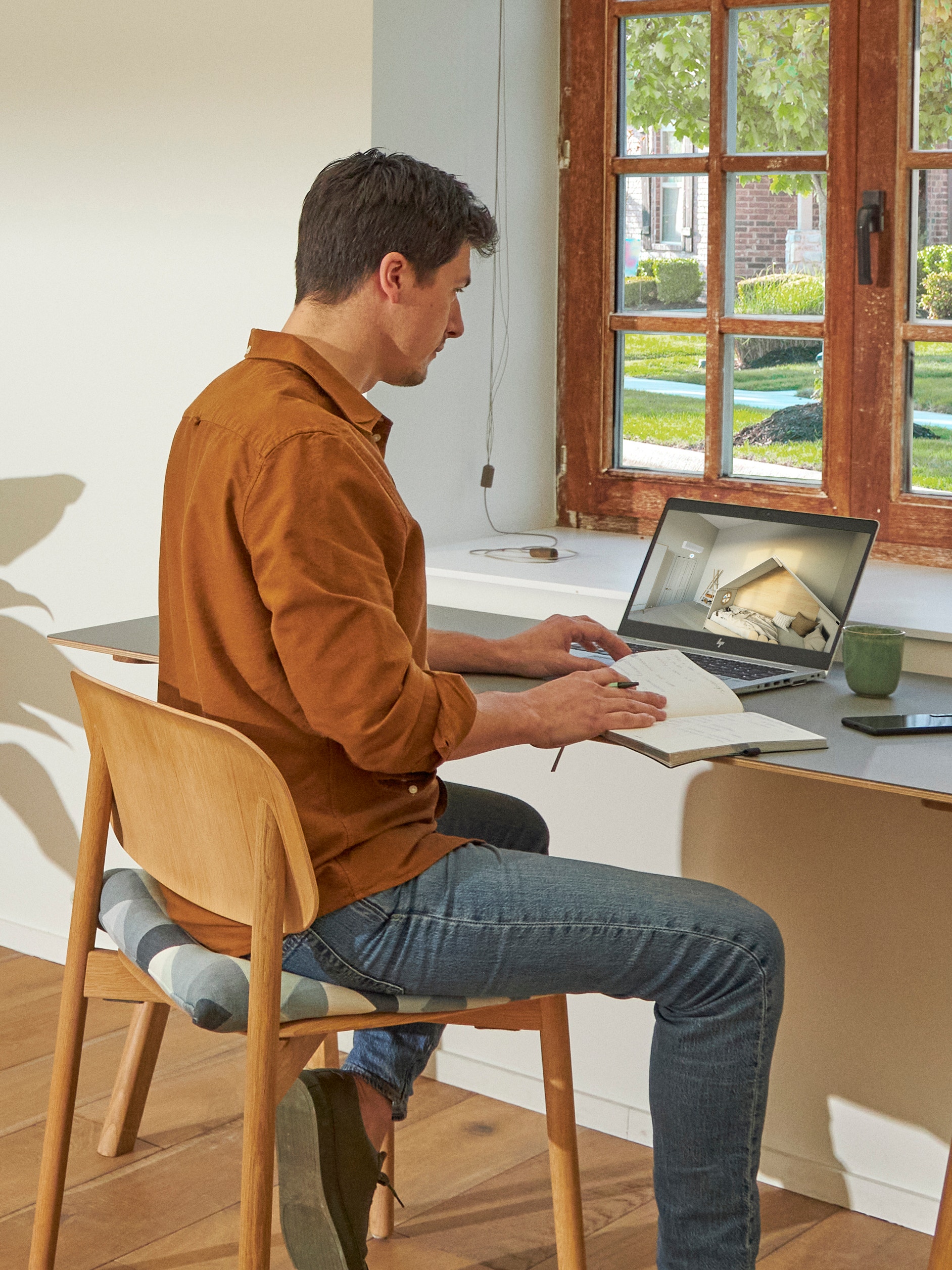 Un uomo in piedi vicino a una finestra mentre guarda i climatizzatori nel centro di esperienza virtuale sul suo computer portatile
