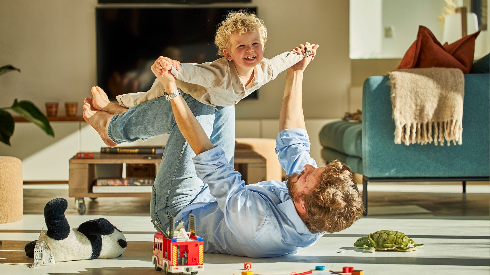 Papà e figlio giocano felici insieme e si godono il calore del riscaldamento a pavimento